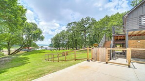 A modern building with a concrete patio, wooden deck, and a staircase leading to an upper level. - Family Fun! Lake Eufaula Home w/ Wraparound Deck (Eufaula)