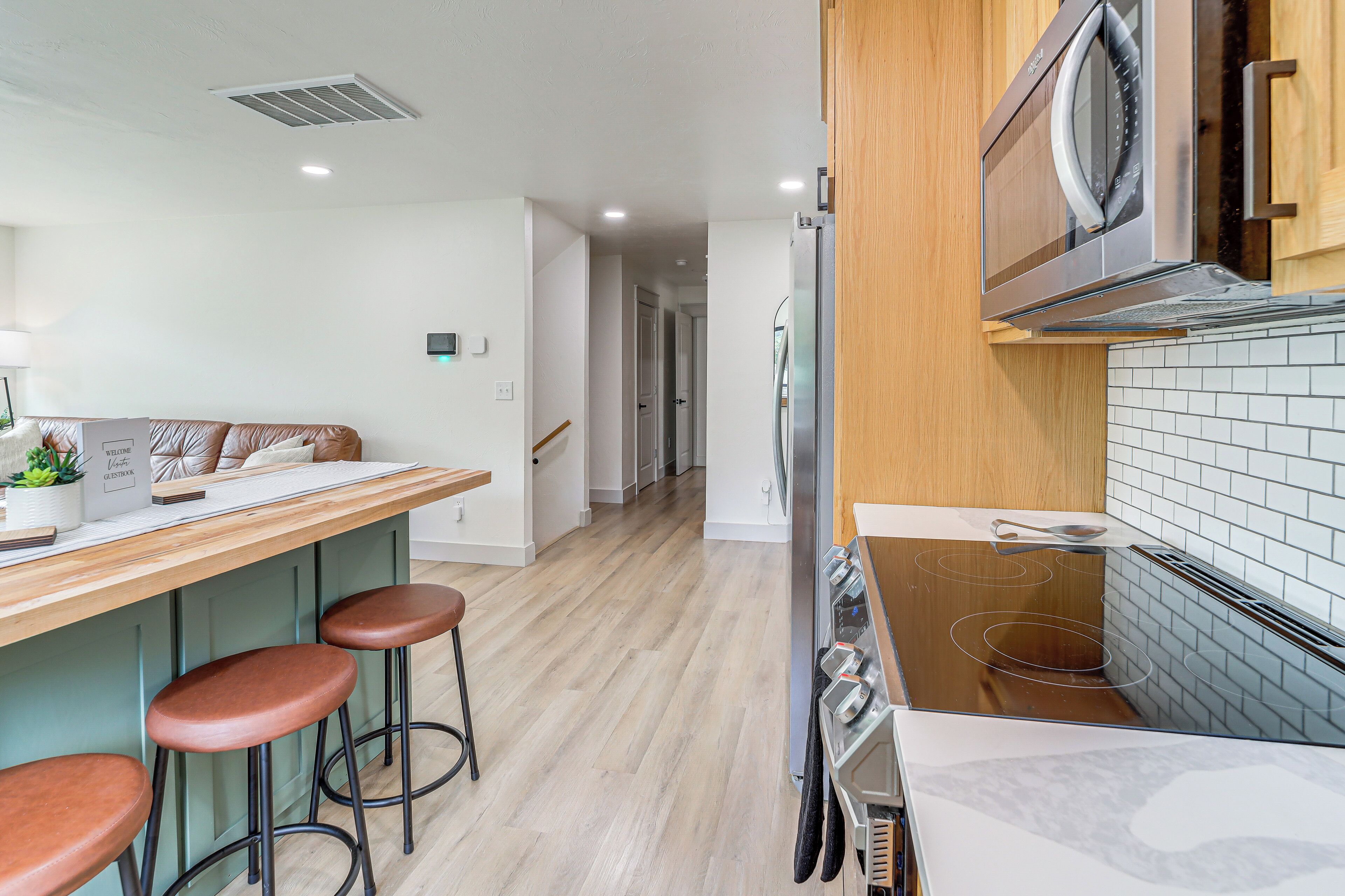 A modern kitchen with a wooden countertop, stainless steel appliances, and a tiled backsplash.