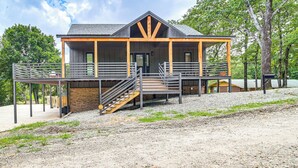 A modern building with a covered porch, a staircase leading to the entrance, and a gravel ground. - Family Fun! Lake Eufaula Home w/ Wraparound Deck (Eufaula)