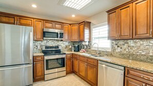 A modern kitchen with wooden cabinets, stainless steel appliances, and a granite countertop.