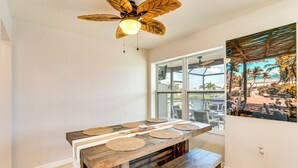 A dining area with a wooden table, woven placemats, and a ceiling fan.
