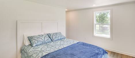 A bedroom with a bed, a window, and a ceiling vent.