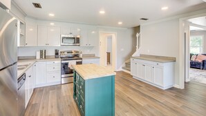 A modern kitchen with white cabinetry, a central island, and a stainless steel refrigerator. - Walk to Winery! Home w/ Patio & Yard in Holt (Holt)