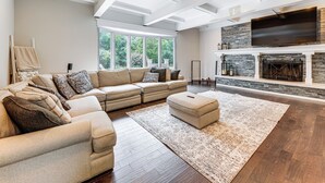 A spacious living room with a sectional sofa, a fireplace, and a large TV. - 7,100 Sq Ft Retreat w/ Gazebo + Koi Pond in Wayne! (Wayne)