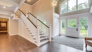 A spacious foyer with a wooden staircase, a large entry door, and a view of the outdoors. - 7,100 Sq Ft Retreat w/ Gazebo + Koi Pond in Wayne! (Wayne)