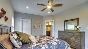 Un dormitorio con cama, cómoda, ventilador de techo y puerta que da a un baño.