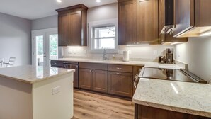 Una cocina moderna con armarios de madera, encimera de mármol y electrodomésticos integrados.