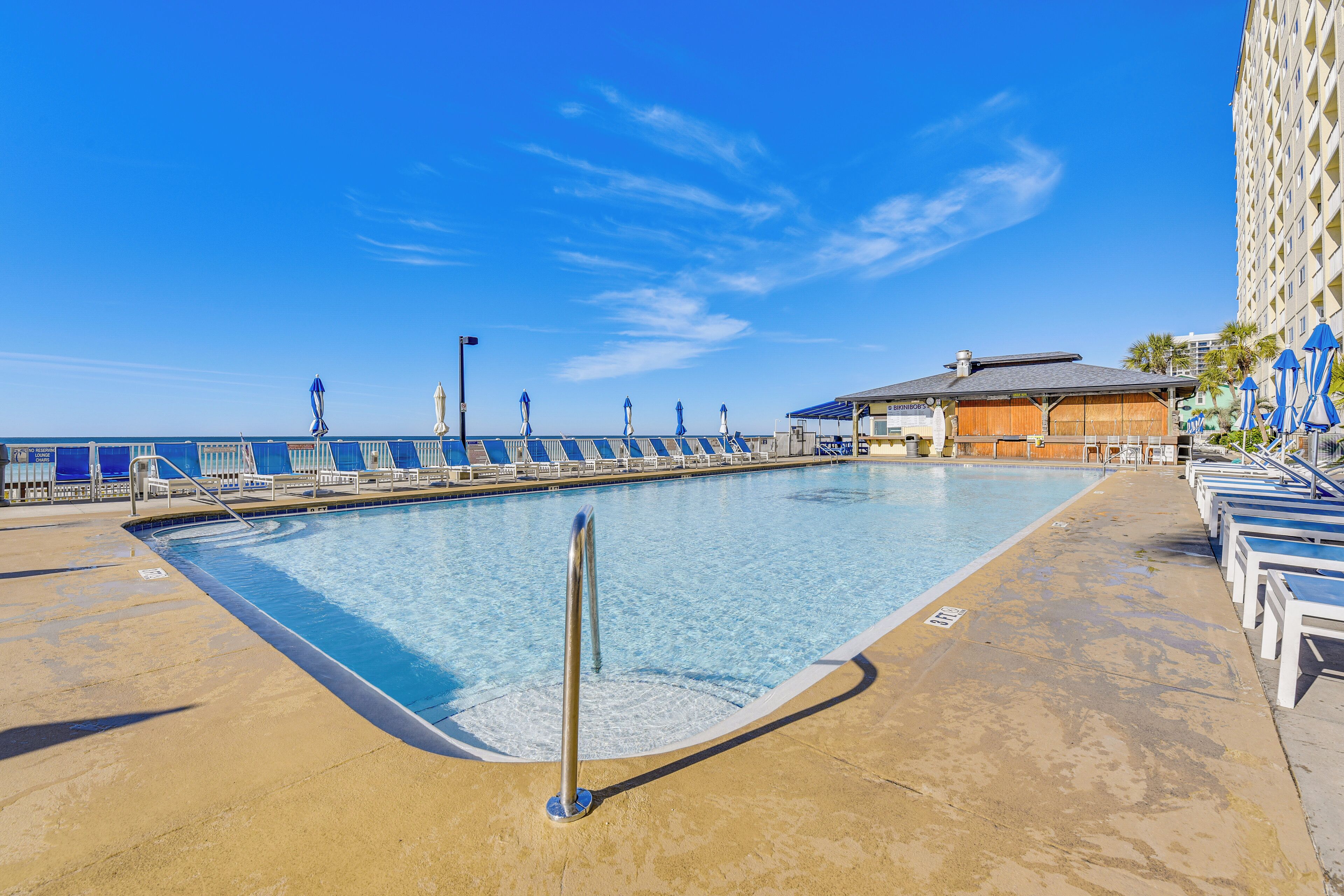 A swimming pool with a deck area, lounge chairs, and a building with a sign.