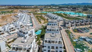A modern residential area with white buildings, a swimming pool, and a clear view of the surrounding landscape. - Santa Rosalia Mar Y Sol - App at the lake (MC)
