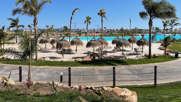 A beach resort with a pool, palm trees, and lounge chairs. - Santa Rosalia Mar Y Sol - App at the lake (MC)