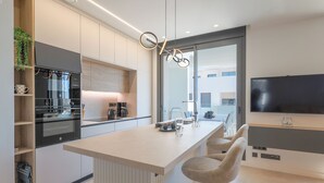 A modern kitchen with a central island, bar stools, a built-in oven, and a large flat-screen TV. - Santa Rosalia Mar Y Sol - App at the lake (MC)