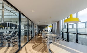 A modern office space with glass walls, wooden flooring, and yellow pendant lights.