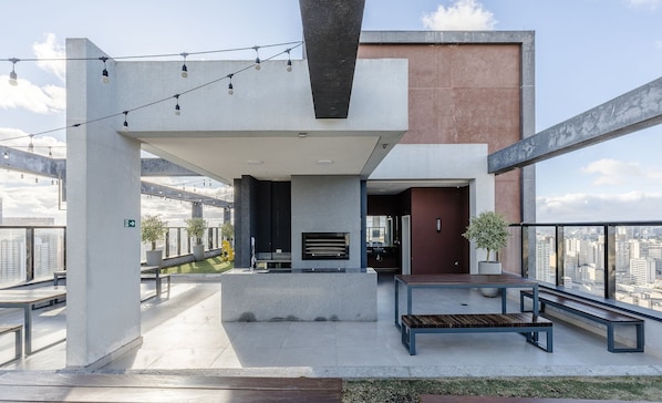 A rooftop terrace with a modern design, featuring a seating area with benches and a fire pit.