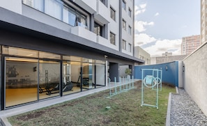 A modern building with large glass windows, a grassy courtyard, and a metal swing set.