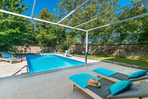 Ein Schwimmbecken mit Liegestühlen und einer Steinmauer.