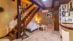 Ein gemütliches Zimmer mit einer Holztreppe, einem Bett, einem kleinen Tisch und einer Steinwand.
