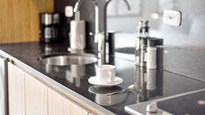 A modern kitchen with a black countertop, stainless steel faucets, and a coffee machine.