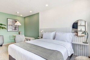 A neatly arranged hotel room with a large bed, a bedside table with a lamp, a chair, and a small desk. - Premium Loft in Bogota (Bogotá)