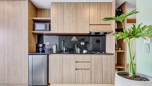 A modern kitchen with wooden cabinets, a built-in microwave, a stainless steel refrigerator, and a potted plant.