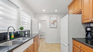A kitchen with a black countertop, wooden cabinets, a white refrigerator, and a sink.