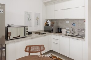 Ett modernt kök med vita skåp, en inbyggd mikrovågsugn, en kaffemaskin och ett diskho.