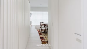 A narrow hallway with a dining area at the end, featuring a patterned rug and wooden chairs. - Studio cond c/ piscina 180m Hard Rock café ESR1912 (Curitiba)