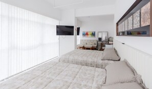 Een slaapkamer met twee bedden, een televisie, een schilderij en een koelkast.