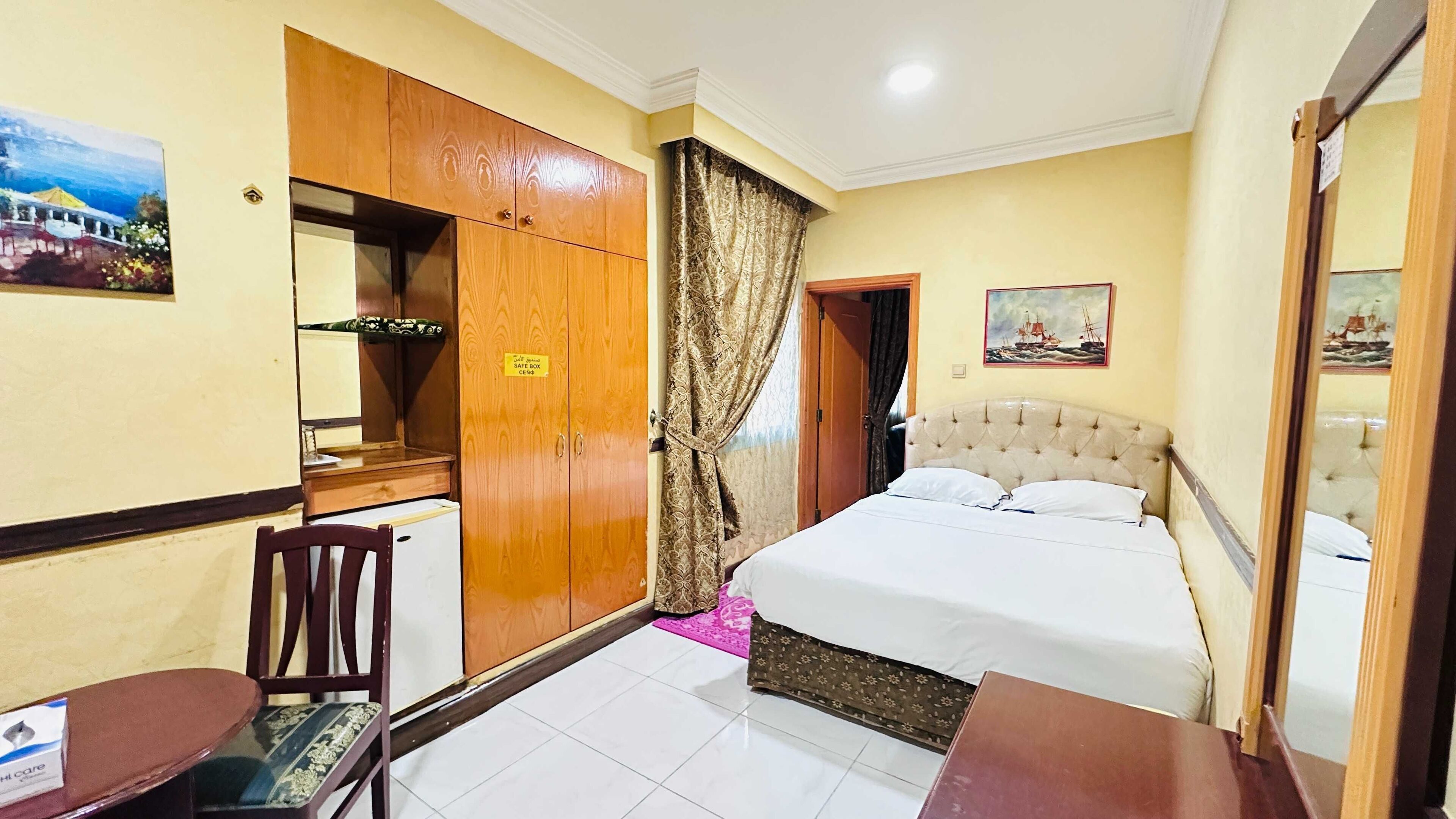 Une chambre d’hôtel comprenant un lit, un coffre-fort, un bureau, une chaise et une petite table.