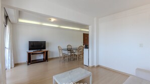 Ein modernes Wohnzimmer mit Flachbildfernseher, Holztisch und Stühlen.