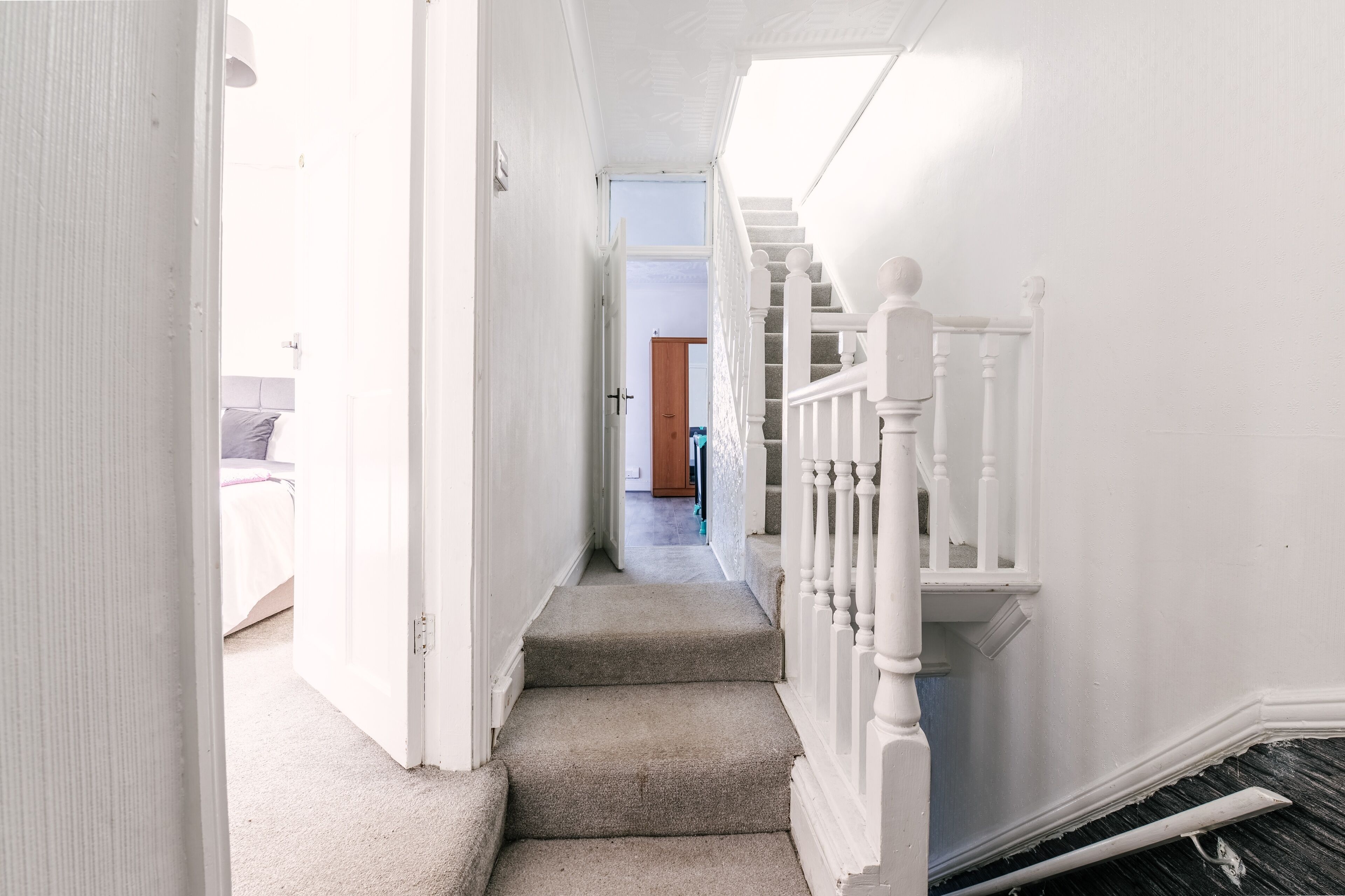 A narrow hallway with a carpeted staircase leading to a landing.
