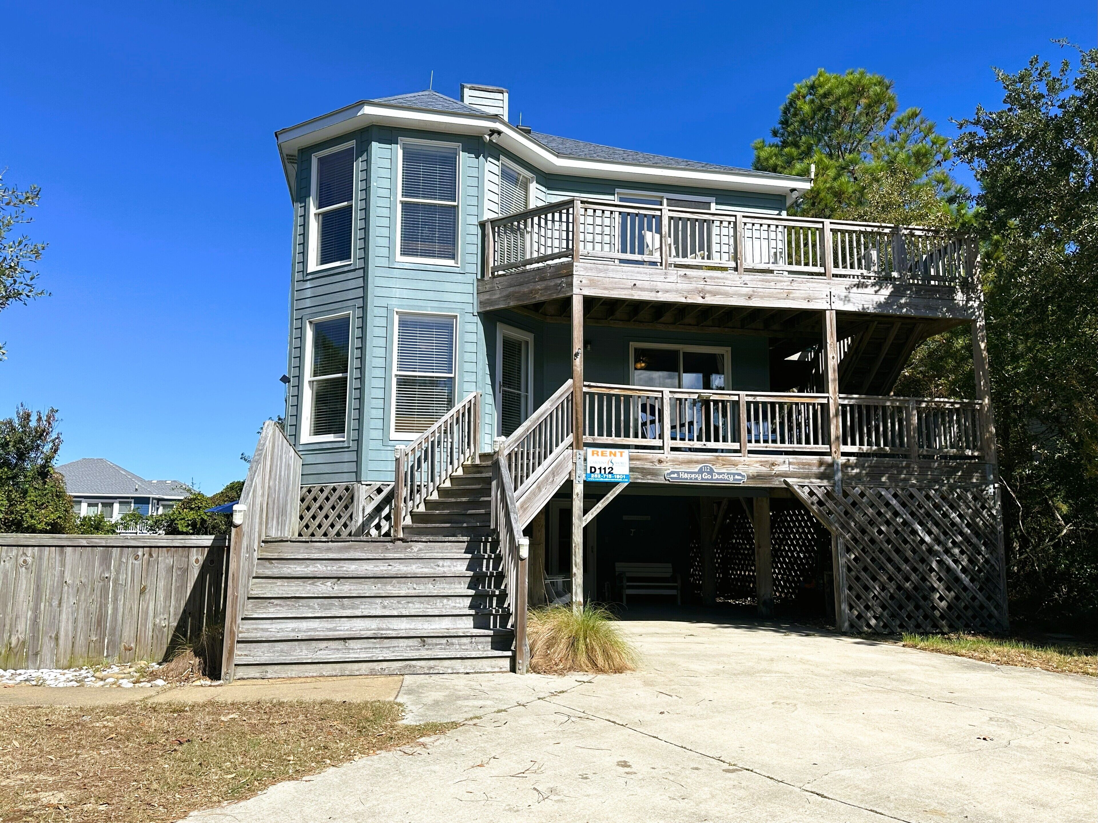 A two-story house with a balcony, a staircase, and a wooden fence.