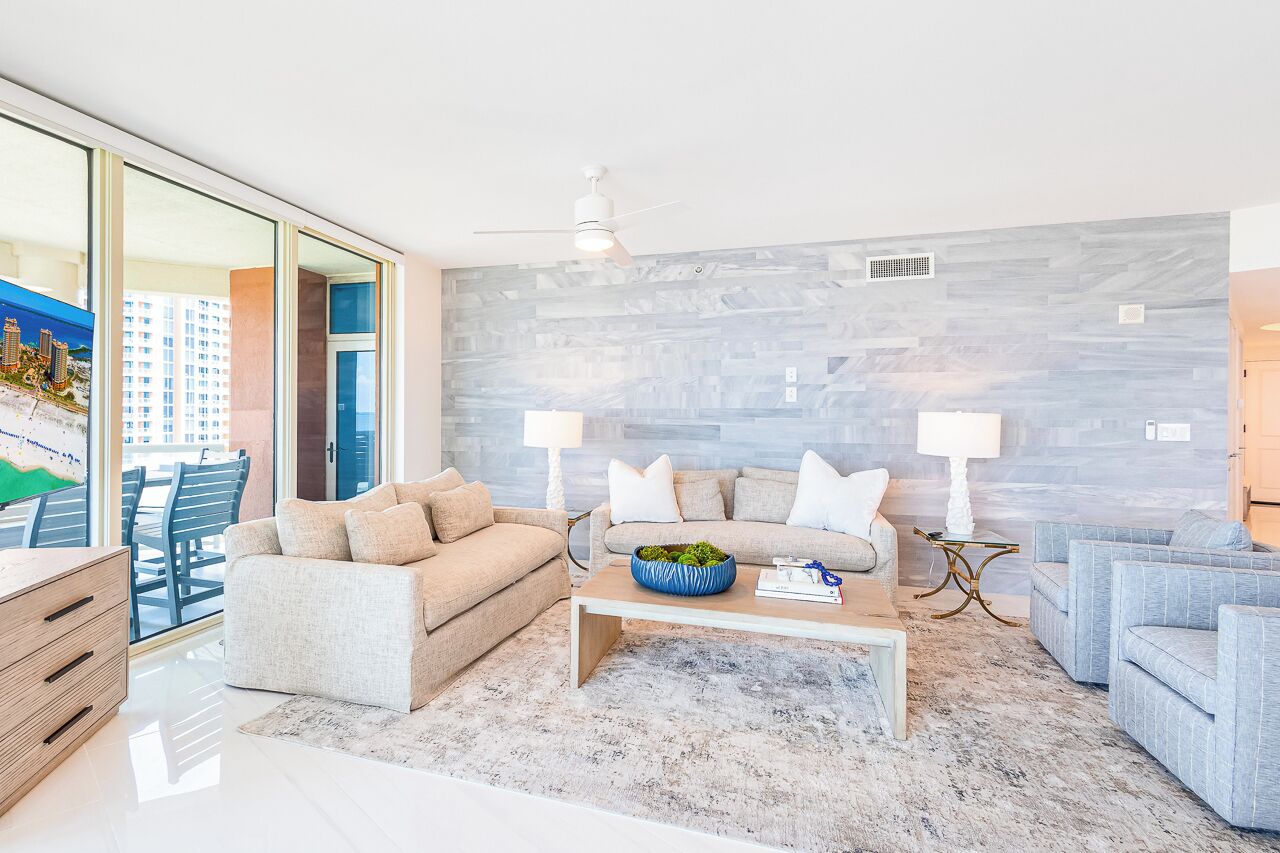 A modern living room with a sofa set, a coffee table, and a view of the city through large windows.