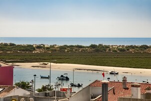 Vista costera con barcos en una playa arenosa y cielo despejado.