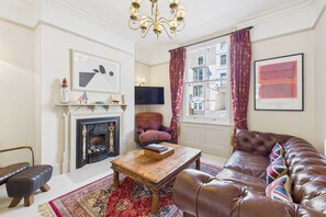 A living room with a fireplace, a sofa, a coffee table, and a television.