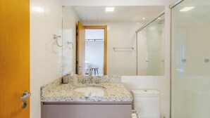 A modern bathroom with a marble sink, a glass shower enclosure, and a toilet. - Loft de luxo com Garagem no Petrópolis AHO1402 (Porto Alegre)