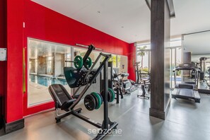 Ein Fitnessstudio mit roten Wänden, Gewichtstrainern und Laufband.