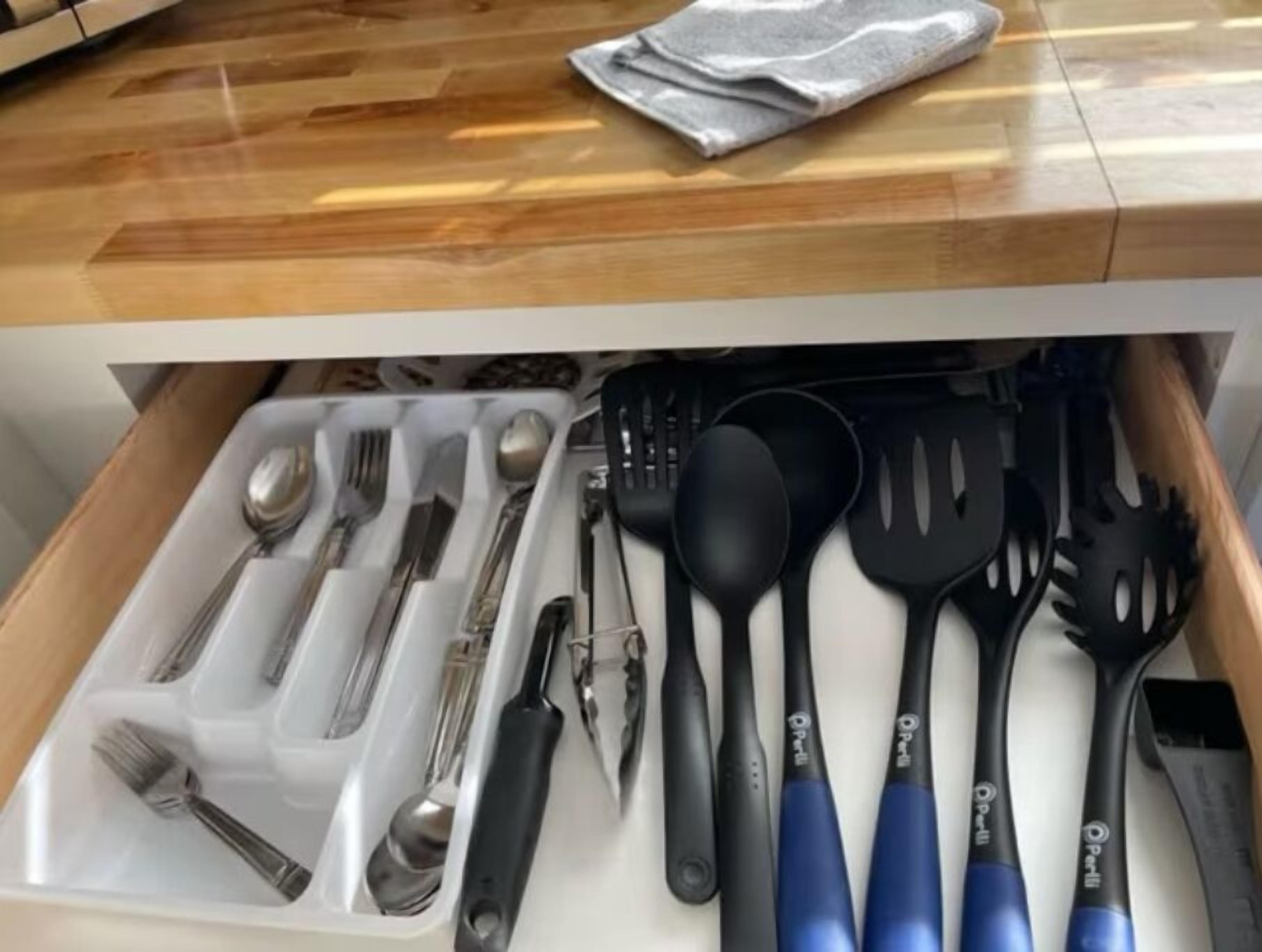 Eine Schublade mit Besteck und Küchenhelfern, darunter Löffel, Gabeln, Messer und Pfannenwender.