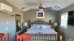 Ein Schlafzimmer mit einem Bett, zwei Nachttischlampen, einem Deckenventilator, einem Fenster und einem roten Sessel.