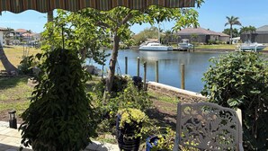 Une vue sur le front de mer, avec un patio abrité, des bateaux amarrés et une végétation luxuriante.