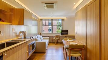 A modern kitchen with wooden cabinets, a dining area with a table and chairs, and a large window providing natural light.