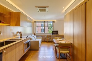 Eine moderne Küche mit Holzausbau, einem Essbereich mit Tisch und Stühlen sowie einem großen Fenster für natürliches Licht.
