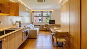 A modern kitchen with wooden cabinets, a built-in oven, and a dining area with a table and chairs. - Beautiful Units in the Auxiliadora Neighborhood in PoA - CEN (Porto Alegre)