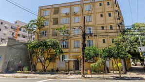 A multi-story building with a yellow facade, air conditioning units, and a gated entrance. - Beautiful Units in the Auxiliadora Neighborhood in PoA - CEN (Porto Alegre)
