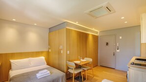 A hotel room with a bed, a dining table with chairs, a small kitchenette, and a door. - Beautiful Units in the Auxiliadora Neighborhood in PoA - CEN (Porto Alegre)
