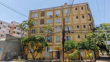 A multi-story building with a yellow facade, air conditioning units, and a gated entrance.