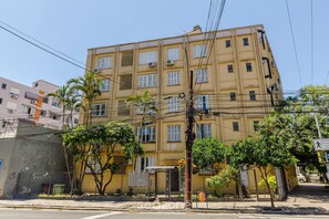 Ein mehrstöckiges Gebäude mit gelber Fassade, Klimaanlagen und einem geschlossenem Eingang.