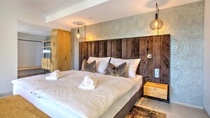 Een moderne slaapkamer met een groot bed, een houten hoofdbord, twee nachtkastjes en een inbouwkast.