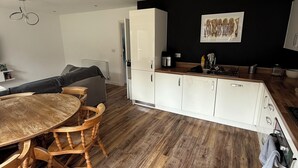 Une cuisine moderne avec des meubles blancs, une table à manger en bois et un mur d’accent noir.