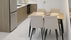Une cuisine moderne dotée d’un réfrigérateur encastré, de meubles en bois, d’un plan de travail blanc et d’un coin repas avec une table et des chaises.