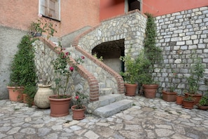 Un escalier en pierre menant à une porte, entouré de plantes en pot et d’un mur de pierre.